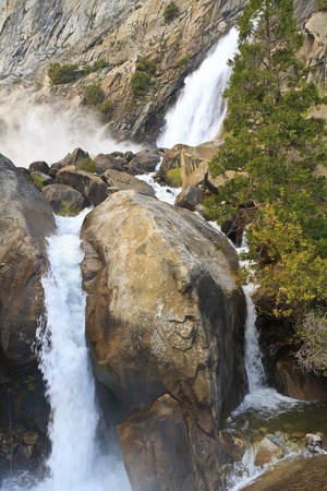 Wapama Falls kicks up clouds of mist as it splits around a boulder in Yosemite National Park, Californiaの写真素材