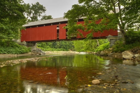 A tranquil North River reflects the Arthur A. Smith covered bridge near Colrain, Massachusetts seen...