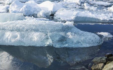 An iceberg reflected in Jokulsarlon glacial lagoon on a sunny winter