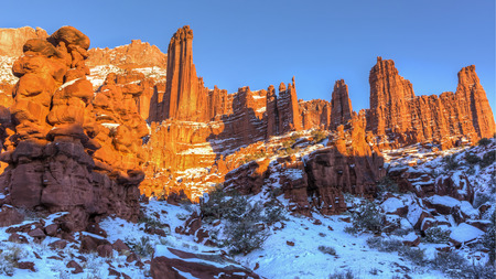 Rock fins rise above the a snowy canyon at the Fisher Towers rock formations near Moab, Utahの写真素材