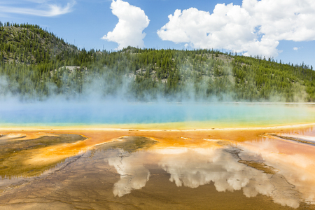 Clouds reflected in the the vivid rainbow colors of the Grand Prismatic Spring in Yellowstone National Park, Wyomingの写真素材