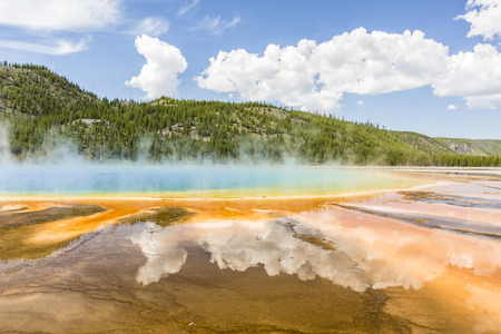 Clouds reflected in the the vivid rainbow colors of the Grand Prismatic Spring in Yellowstone National Park, Wyomingの写真素材