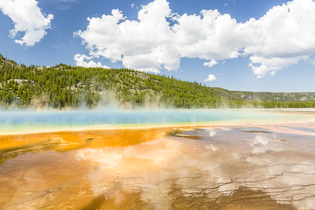 Clouds reflected in the the vivid rainbow colors of the Grand Prismatic Spring in Yellowstone National Park, Wyomingの写真素材