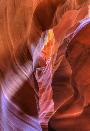 Twisting, striated layers of red sandstone walls of Upper Antelope Canyon lit with dim bounce light in Page, Arizona.の写真素材