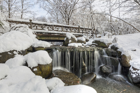 Snowclad Binnen Bridge above silky Binen falls after a Spring snowfall in Prospect Park, Brooklyn, New York.の写真素材