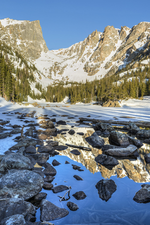 Morning Sun on Hallett Peak is reflected in half frozen Dream Lake in Rocky Mountain National Park, Coloradoの写真素材