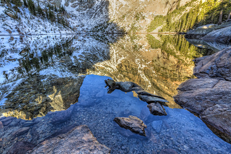 Emerald Lake stones mix with perfect reflections of Hallett Peak at Emerald Lake in Rocky Mountain National Park.の写真素材