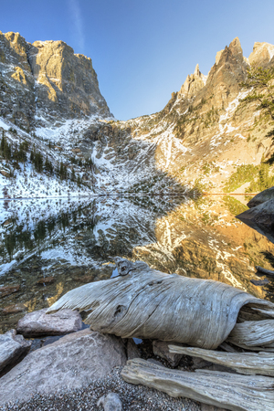 Interesting driftwood on the shores, with mountains mirrored in Emerald Lake in Rocky Mountain National Park.の写真素材