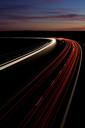 Cars moving fast on a highway at night / at dusk (motion blurred image)