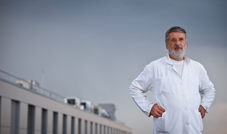renowned scientist/doctor standing on the roof of the research center/hospital looking confident (color toned image)の写真素材
