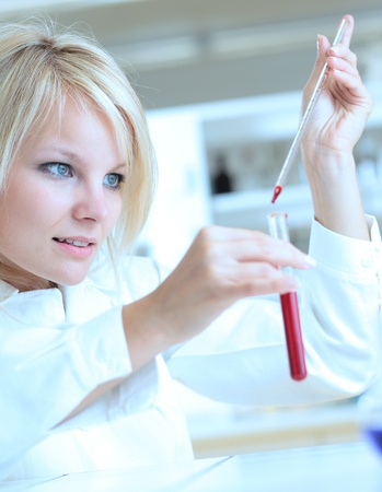 Closeup of a female researcher holding up a test tube and a retort and carrying out experimentsの写真素材