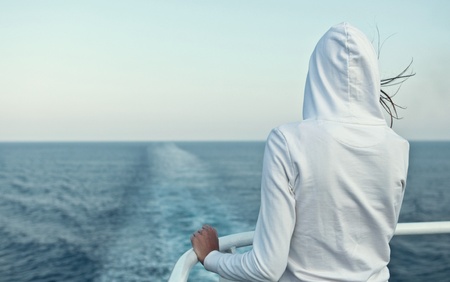 Young woman looking at the ocean from a fast going linerの写真素材