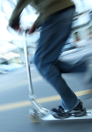 Boy on a scooter going fast (panning technique used -> motion blurred photo with some sharpness on...