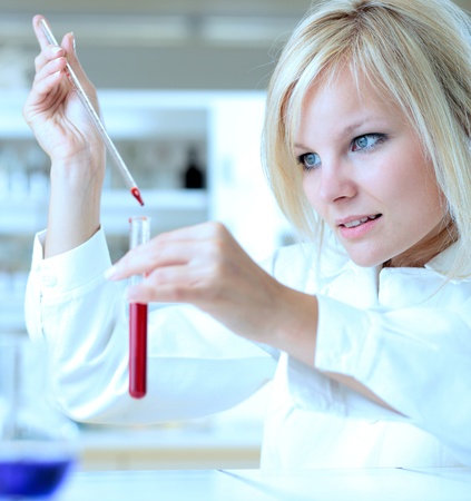 Closeup of a female researcher holding up a test tube and a retort and carrying out experiments Closeup of a female researcher holding up a test tube and a retort and carrying out experiments