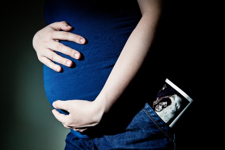 maternity concept - expectant young woman with sonography photo of her child in her pocket