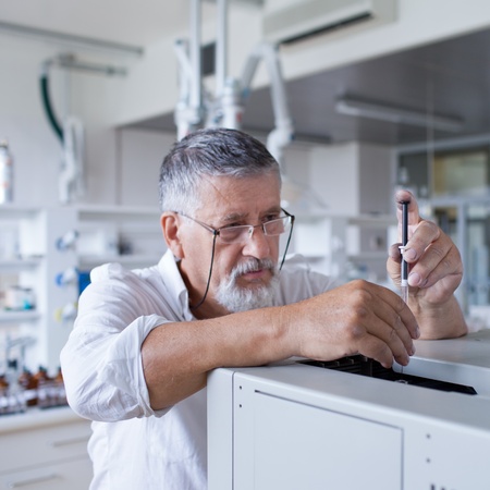 senior male researcher carrying out scientific research in a lab using a gas chromatograph (shallow DOF; color toned image)の写真素材