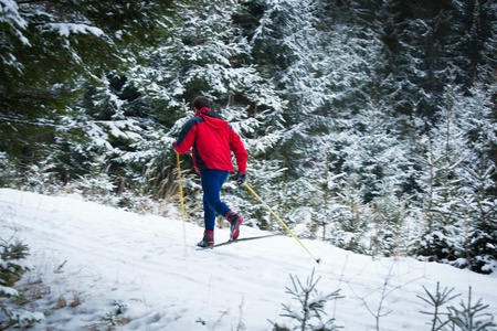 young man cross-country skiing on a snowy forest trail (motion blurred & color toned image)の写真素材