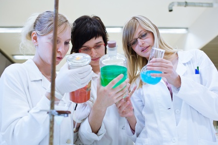 three researchers/chemistry students carrying out research in a chemistry lab (color toned image;...
