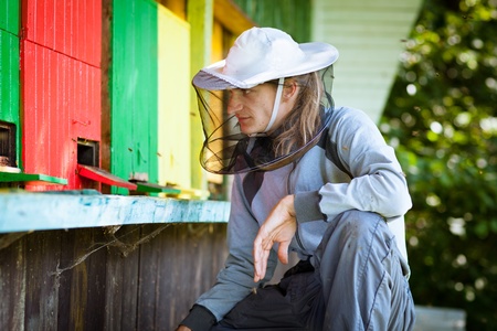 Beekeeper by an apiary observing carefully his beesの写真素材