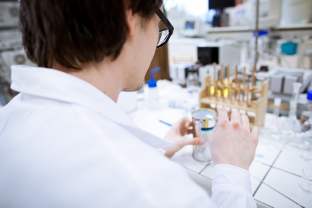 young, male researcher/chemistry student carrying out scientific research in a lab (shallow DOF;...