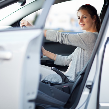 Pretty young woman driving her new car