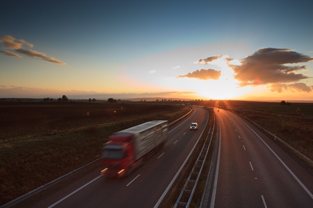 highway traffic - motion blurred truck on a highway/motorway/speedway at dusk (color toned image)の写真素材