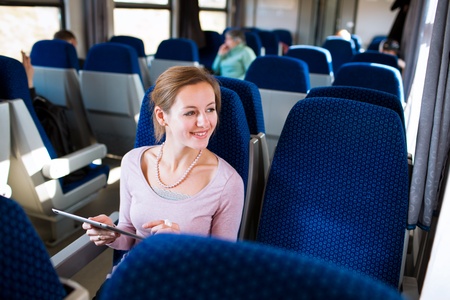 Young woman using her tablet computer while traveling by trainの写真素材