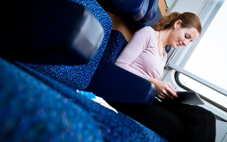 Young woman reading a book while on a trainの写真素材