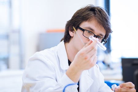 young, male researcher/chemistry student carrying out scientific research in a lab (shallow DOF; color toned image)の写真素材