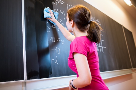 pretty young college student writing on the chalkboard/blackboard during a math class (color toned image; shallow DOF)の写真素材