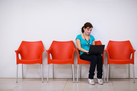 Pretty young female student with laptop on college/university campusの写真素材