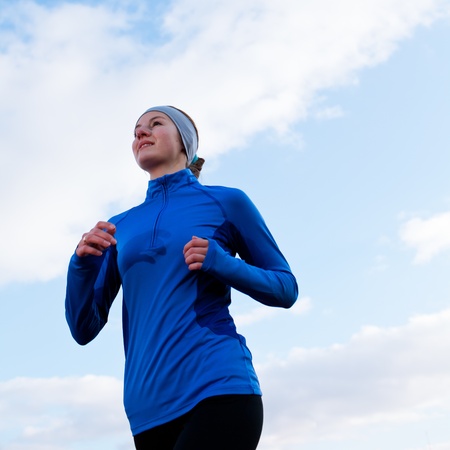 Portrait of a woman running against against blue skyの写真素材