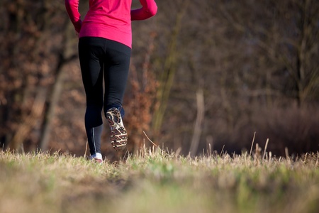 Jogging outdoors in a meadow (shallow dof, focus on the running shoe)