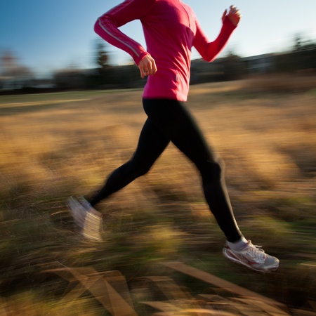 Young woman running outdoors in a city park on a cold fall/winter day (motion blurred image)