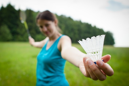 Pretty, young woman playing badminton in a city park on a lovely summer day (shallow DOF)の写真素材