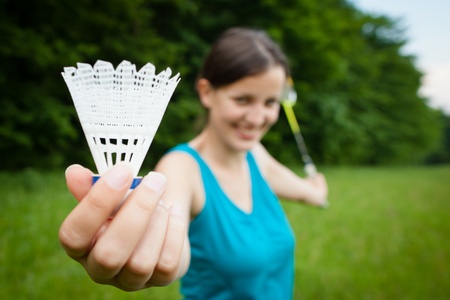 Pretty, young woman playing badminton in a city park on a lovely summer day (shallow DOF)の写真素材