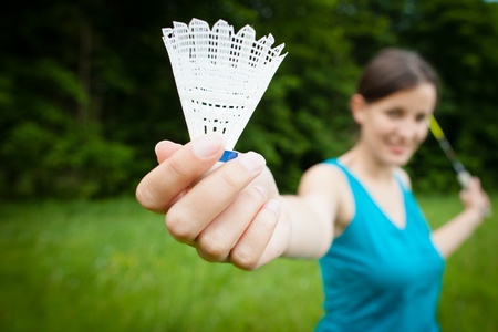 Pretty, young woman playing badminton in a city park on a lovely summer day (shallow DOF)の写真素材