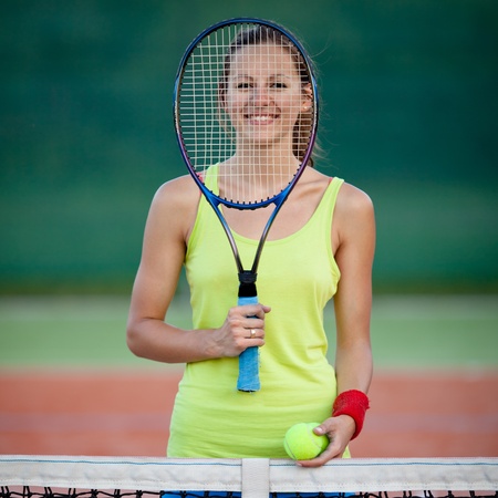 pretty, young female tennis player on the tennis court (shallow DOF, selective focus)の写真素材