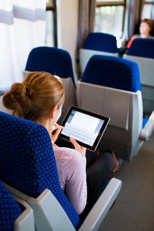 Young woman using her tablet computer while traveling by trainの写真素材
