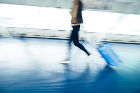 Airport rush: people with their suitcases walking along a corridor (motion blurred image; color toned image)の写真素材