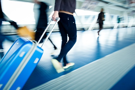 Airport rush: people with their suitcases walking along a corridor (motion blurred image; color toned image)の写真素材