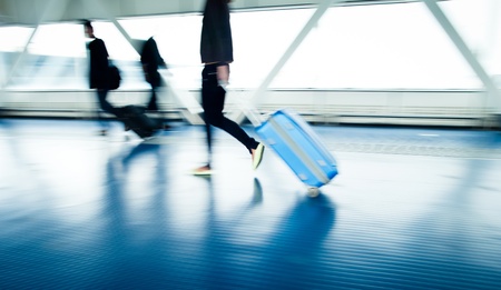 Airport rush: people with their suitcases walking along a corridor (motion blurred image; color toned image)の写真素材