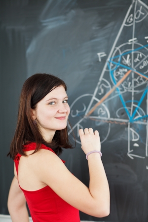 pretty young college student writing on the chalkboard/blackboard during a math class  の写真素材
