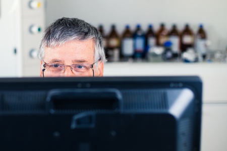 Senior researcher using a computer in the lab while working on an experiment (color toned image)の写真素材