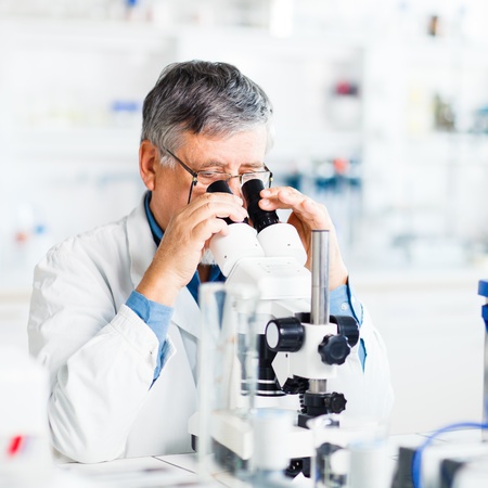 senior male researcher carrying out scientific research in a lab using a microscope (shallow DOF;...