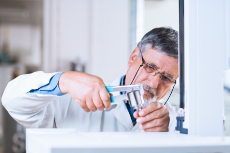 senior male researcher carrying out scientific research in a lab using a gas chromatograph 