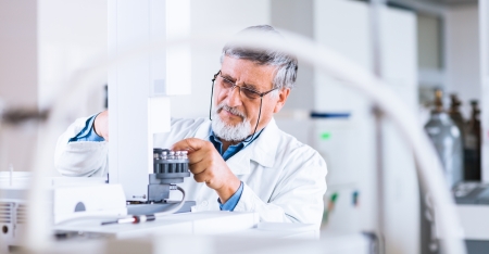 senior male researcher carrying out scientific research in a lab using a gas chromatograph の写真素材