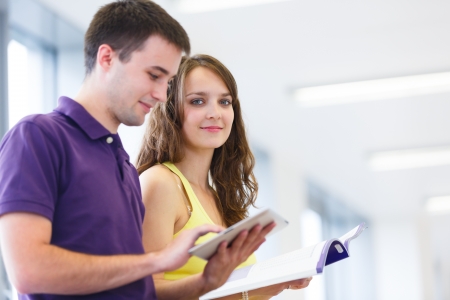 Two college students in library, reading books, using tablet computerの写真素材