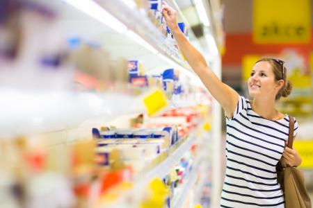 Beautiful young woman shopping for diary products at a grocery store/supermarket (color toned image) Beautiful young woman shopping for diary products at a grocery store/supermarket (color toned image)