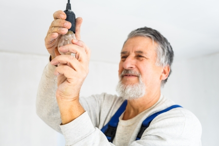 Senior man installing a bulb in a freshly renovated appartmentの写真素材